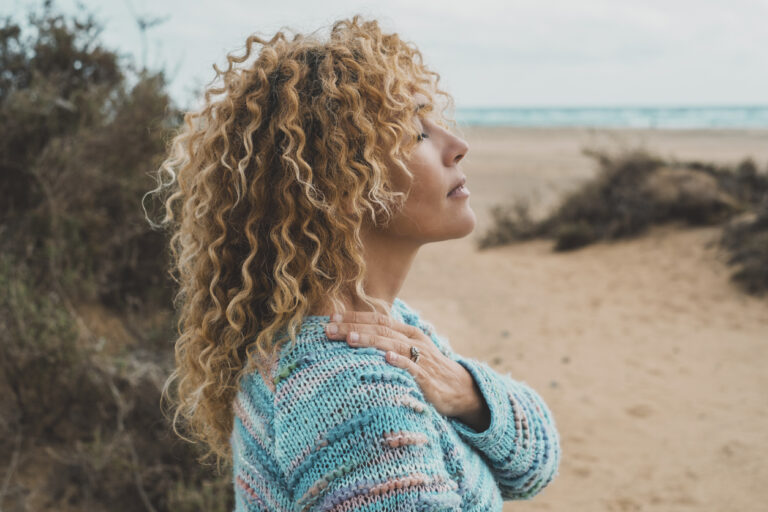 One woman enjoy inner balance and meditation leisure outdoor activity alone feeling nature hugging herself at the beach. Side portrait of zen lifestyle and happiness female people